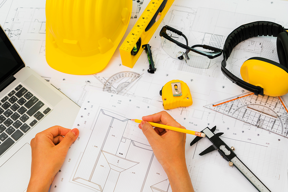 Hand over Construction plans with yellow helmet and drawing tool